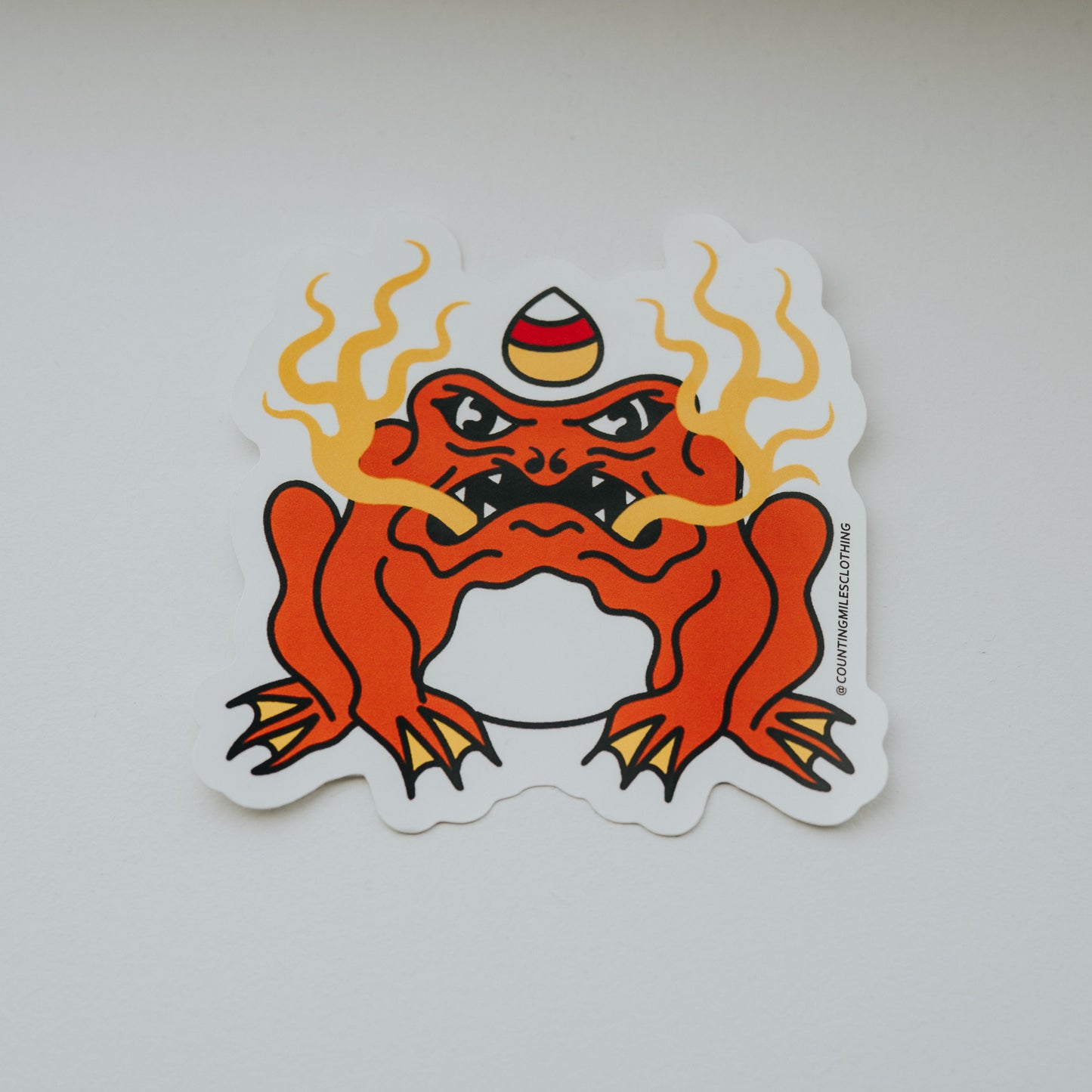Sticker of a red creature with flames on a white surface