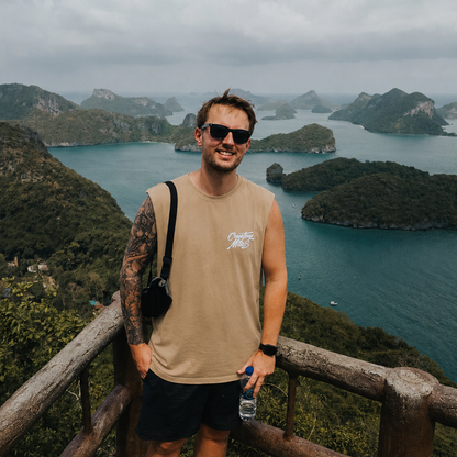 Man standing on a wooden platform overlooking a scenic view of islands and water.
